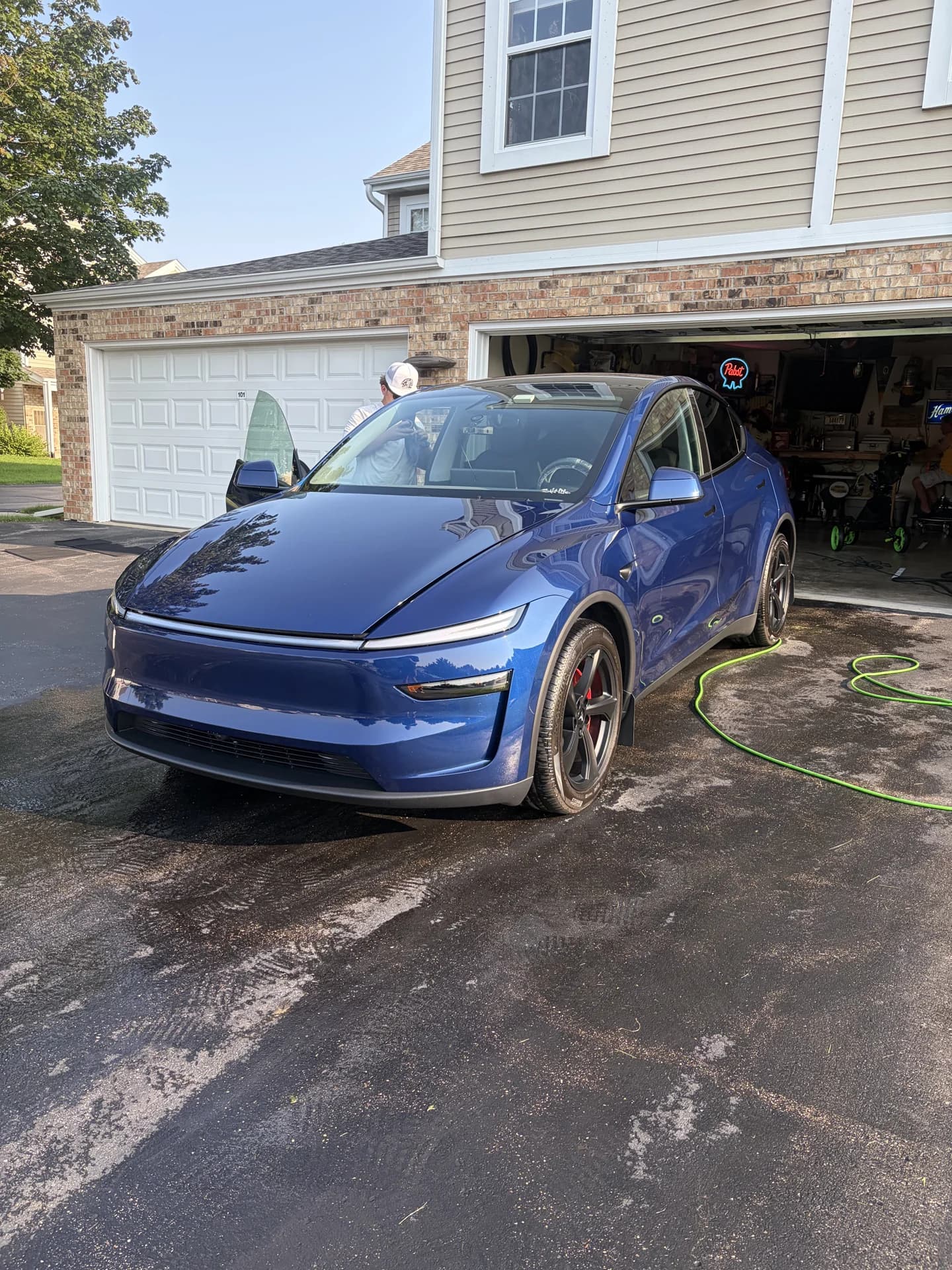 Blue sedan after an exterior wash in a residential driveway